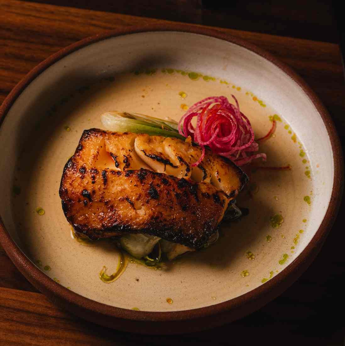 Miso-glazed black cod with charred scallion and pickled radish