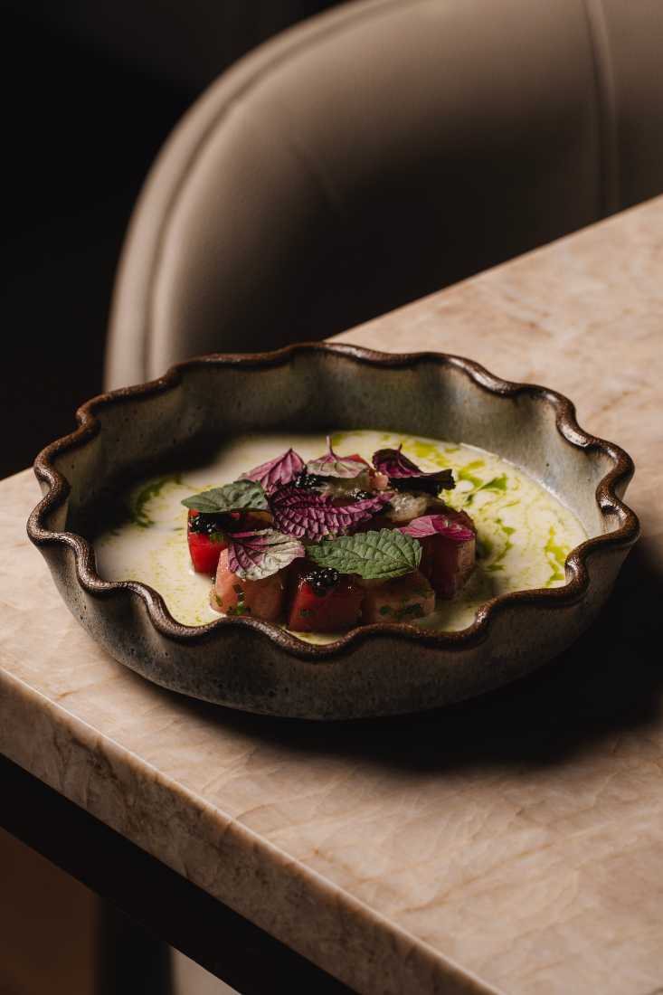 Tartare with caviar and shiso in a ruffled dark ceramic bowl