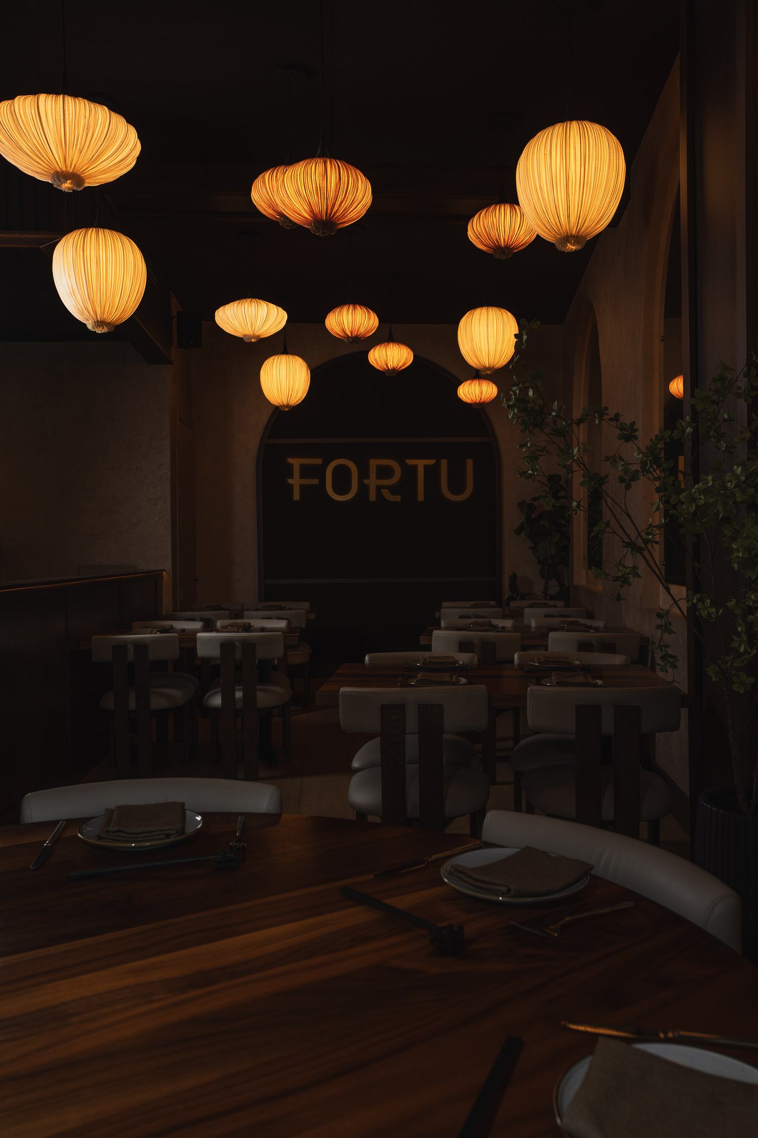 The Fortu dining room at night, silk lanterns glowing above set tables and the FORTU sign
