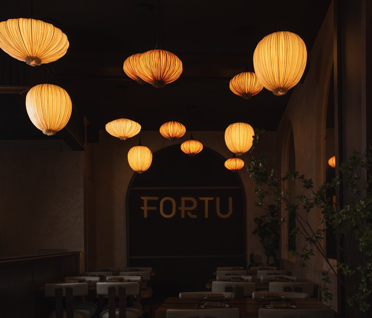 The Fortu dining room at night, silk lanterns above set tables