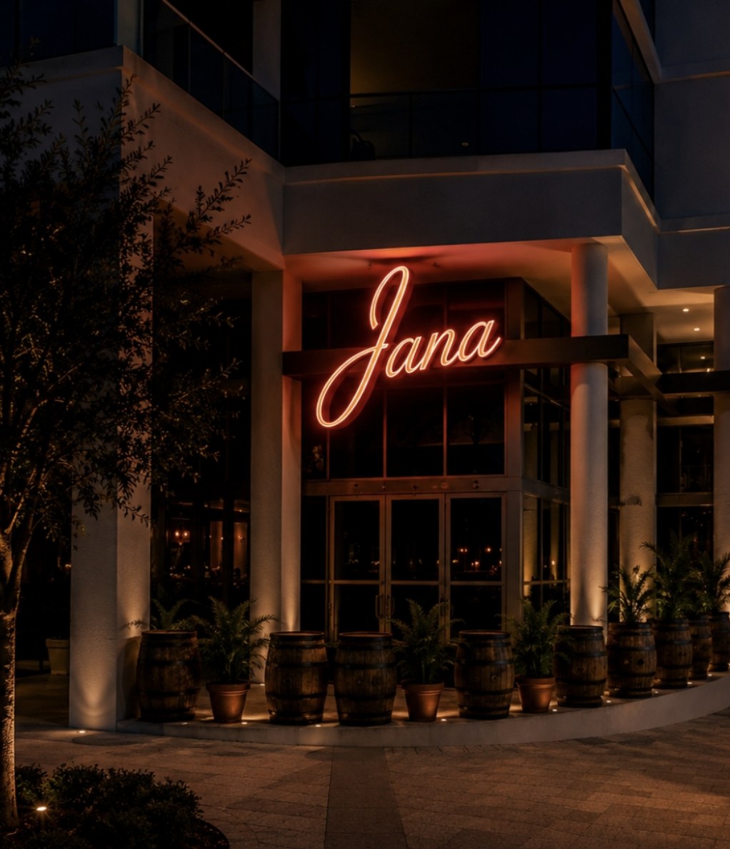 The Jana Steakhouse entrance at night, neon script sign above the doors
